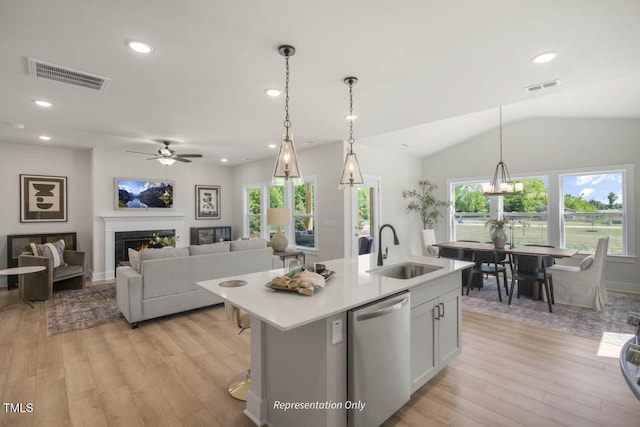 kitchen with a lit fireplace, stainless steel dishwasher, a sink, and visible vents