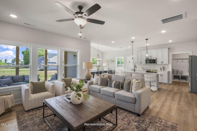 living room with a ceiling fan, recessed lighting, visible vents, and light wood finished floors