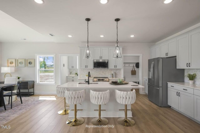 kitchen featuring a kitchen breakfast bar, stainless steel appliances, a sink, and light countertops