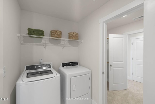 laundry area with laundry area, visible vents, separate washer and dryer, and light colored carpet