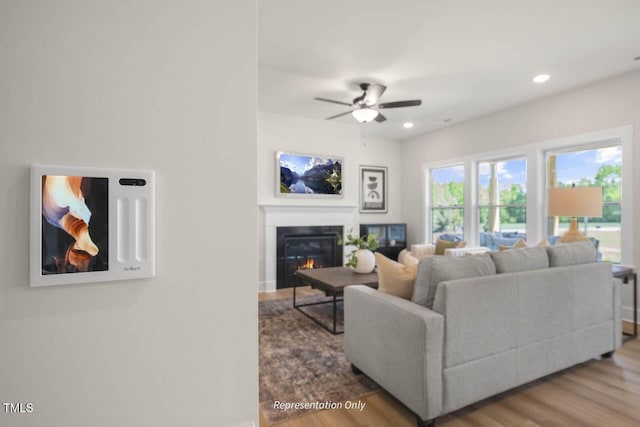 living area with ceiling fan, wood finished floors, a glass covered fireplace, and recessed lighting