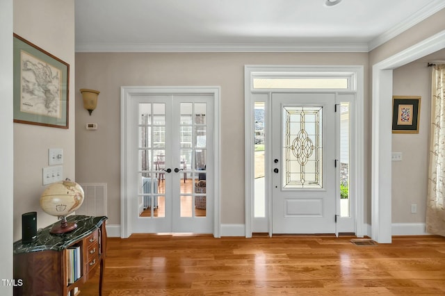 entrance foyer with light wood-style floors, baseboards, crown molding, and french doors