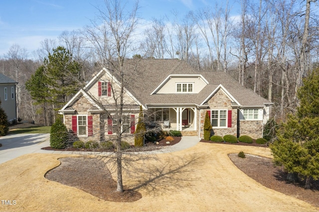 view of front of property featuring stone siding, a shingled roof, and dirt driveway