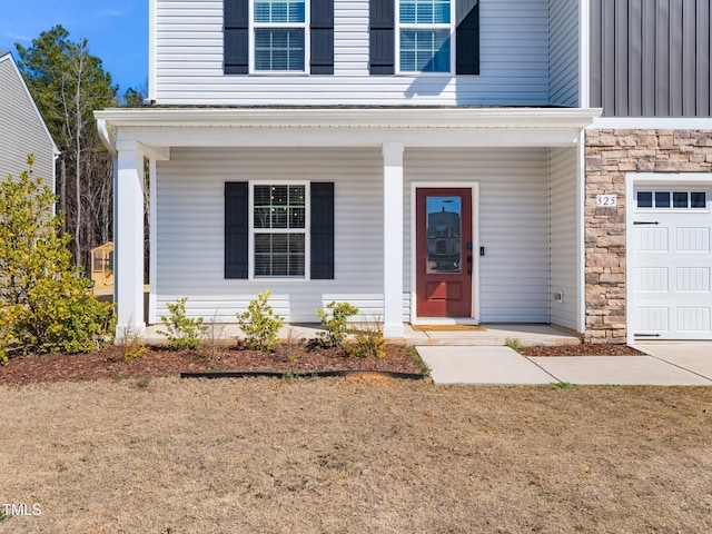 view of exterior entry featuring stone siding, covered porch, and a garage