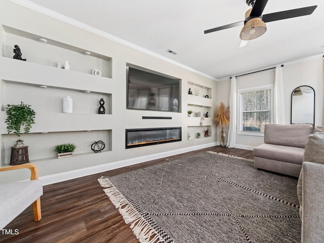 living room featuring a glass covered fireplace, built in shelves, ornamental molding, and wood finished floors