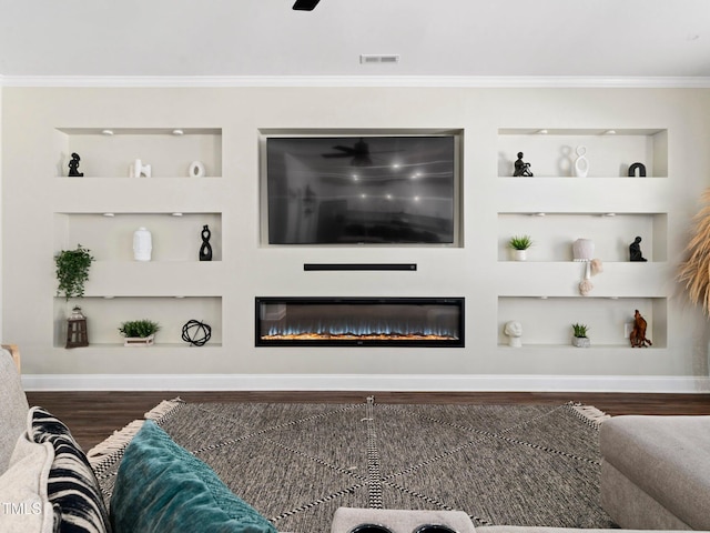 living room with visible vents, built in shelves, ornamental molding, wood finished floors, and a glass covered fireplace