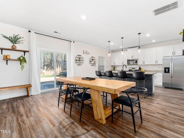 dining space featuring crown molding, recessed lighting, wood finished floors, and visible vents