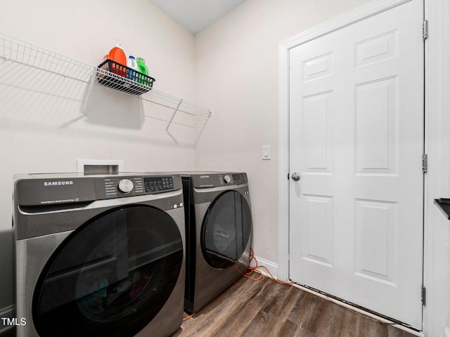 washroom with baseboards, wood finished floors, washing machine and dryer, and laundry area