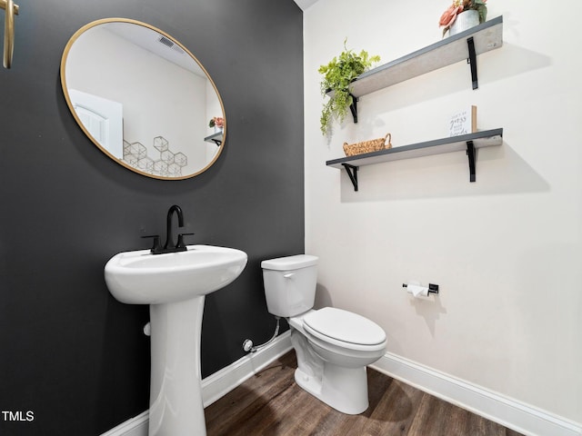 bathroom featuring toilet, wood finished floors, baseboards, and a sink