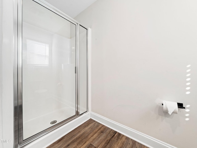 bathroom featuring a stall shower, baseboards, and wood finished floors