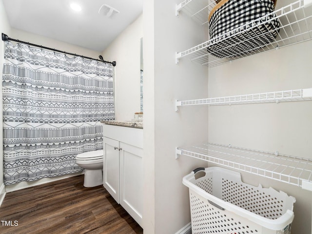 full bath with visible vents, toilet, a shower with curtain, wood finished floors, and vanity