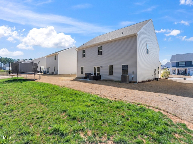 rear view of house with a patio area, a lawn, cooling unit, and a trampoline