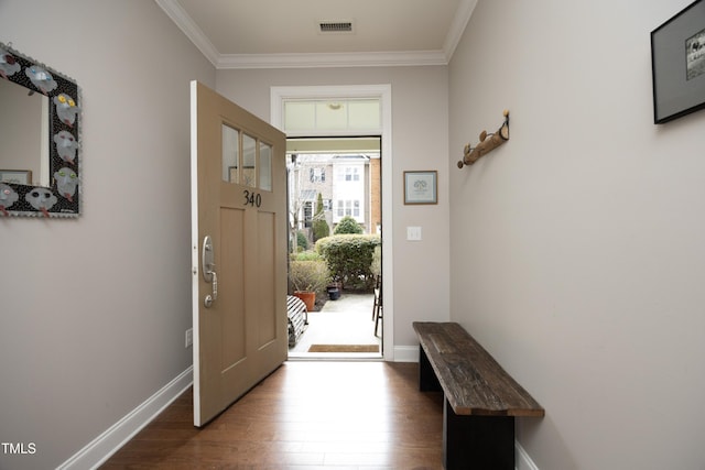 foyer entrance featuring ornamental molding, visible vents, baseboards, and wood finished floors