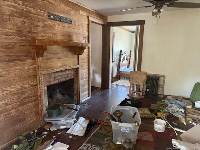 living room featuring a brick fireplace, a ceiling fan, wood finished floors, and wood walls