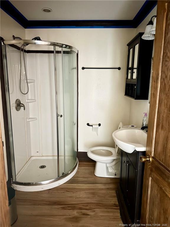 full bathroom featuring toilet, ornamental molding, a stall shower, vanity, and wood finished floors