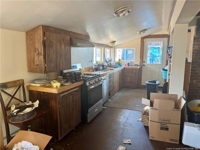 kitchen with stainless steel appliances, lofted ceiling, and wall chimney exhaust hood