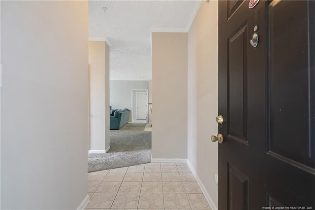 foyer entrance featuring light tile patterned flooring, crown molding, a textured ceiling, and baseboards