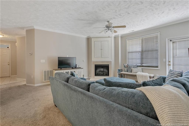 living room with light carpet, a fireplace, visible vents, and crown molding