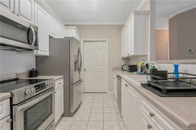 kitchen with stainless steel appliances, crown molding, light countertops, white cabinetry, and backsplash