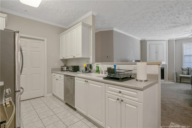 kitchen with stainless steel appliances, a peninsula, a sink, white cabinetry, and light countertops