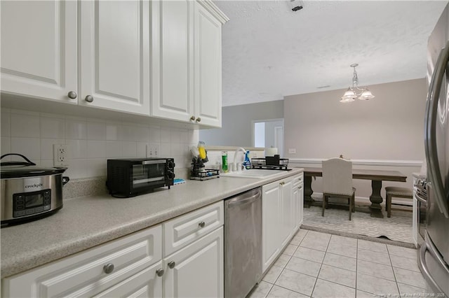 kitchen featuring light tile patterned floors, a sink, white cabinets, appliances with stainless steel finishes, and decorative backsplash