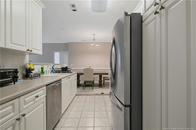 kitchen with light tile patterned flooring, a sink, white cabinetry, light countertops, and appliances with stainless steel finishes