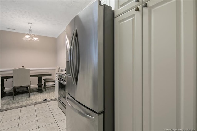 kitchen with decorative light fixtures, a notable chandelier, stainless steel appliances, light tile patterned flooring, and a textured ceiling