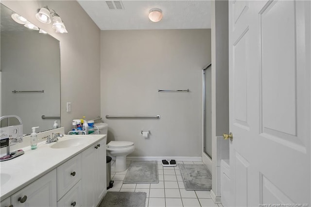 bathroom with double vanity, toilet, tile patterned floors, an enclosed shower, and a sink