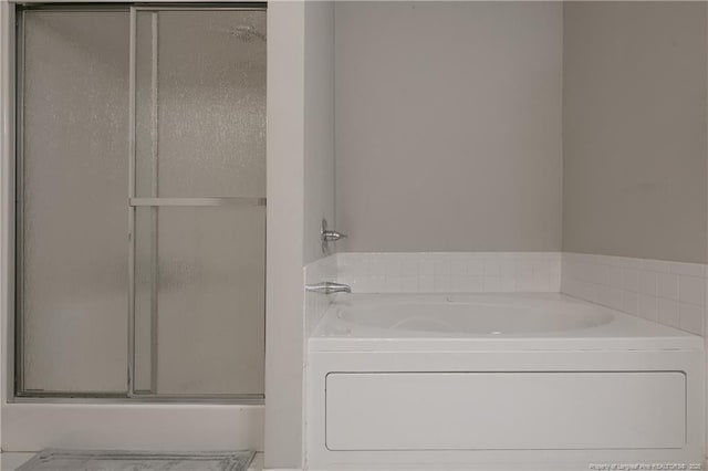 bathroom featuring a stall shower and a bath