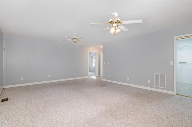 spare room featuring light colored carpet, a ceiling fan, visible vents, and baseboards