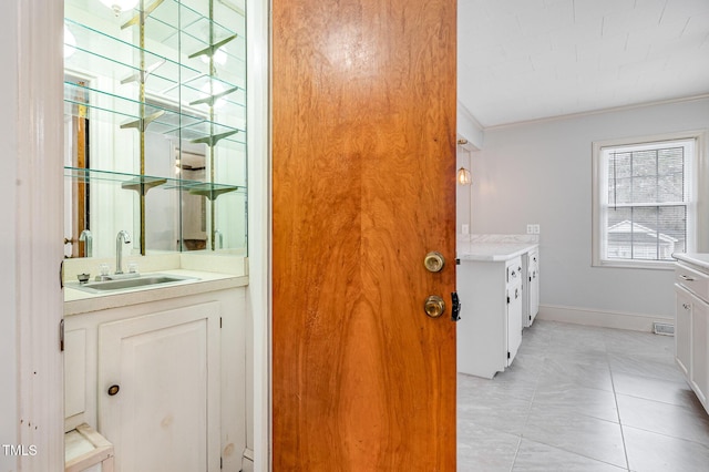 bathroom featuring a sink, baseboards, two vanities, and ornamental molding