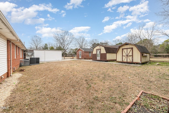 view of yard featuring a storage shed, cooling unit, fence, and an outdoor structure