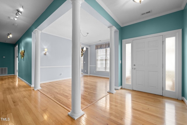 foyer entrance with light wood-style flooring, decorative columns, visible vents, and ornamental molding