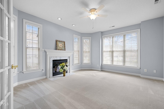 unfurnished living room featuring a high end fireplace, baseboards, and carpet