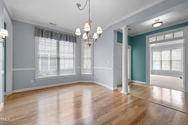 unfurnished dining area with visible vents, ornamental molding, plenty of natural light, ornate columns, and wood-type flooring