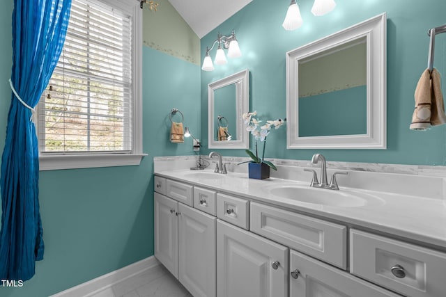 full bathroom with double vanity, baseboards, lofted ceiling, and a sink