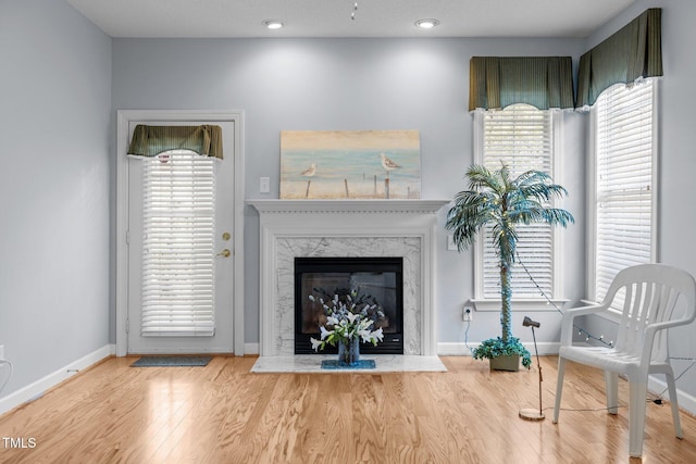 living area featuring recessed lighting, a premium fireplace, baseboards, and wood finished floors