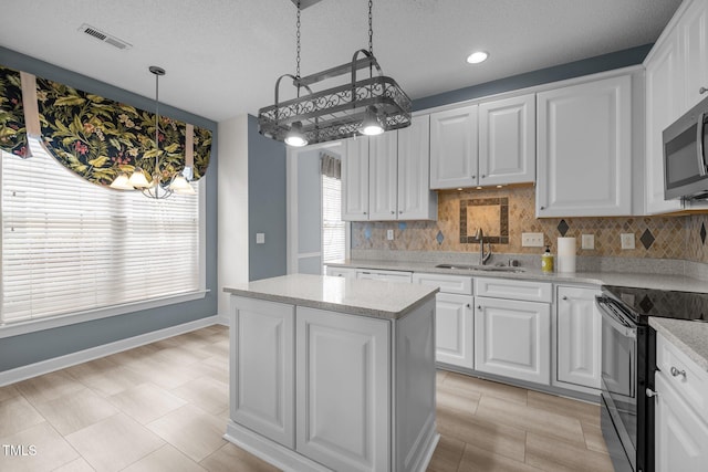 kitchen featuring decorative backsplash, stainless steel microwave, black range with electric cooktop, and a sink