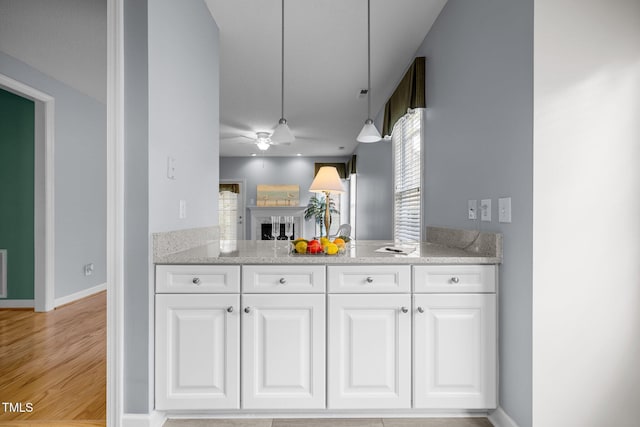 kitchen featuring baseboards, light wood-style flooring, hanging light fixtures, white cabinets, and a ceiling fan