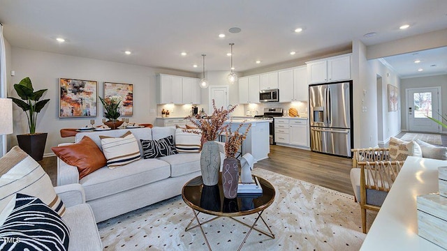 living area featuring light wood-type flooring, baseboards, crown molding, and recessed lighting