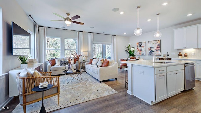 kitchen with light countertops, decorative backsplash, open floor plan, a sink, and wood finished floors