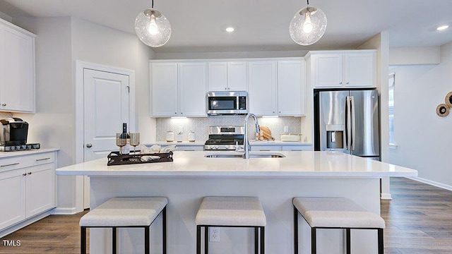 kitchen featuring appliances with stainless steel finishes, a sink, white cabinetry, and decorative backsplash