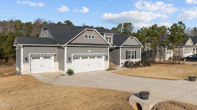 view of front of house featuring driveway, an attached garage, a front yard, and roof with shingles