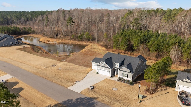 drone / aerial view with a forest view and a water view