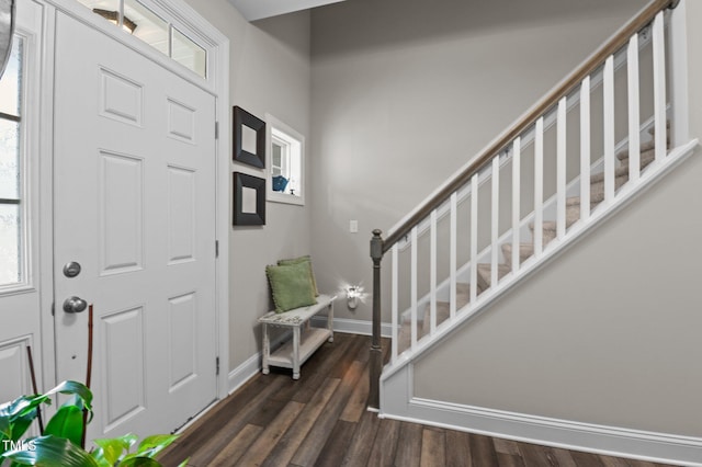 foyer entrance with stairs, baseboards, and dark wood finished floors