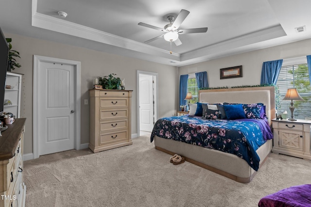 bedroom with a tray ceiling, multiple windows, and visible vents