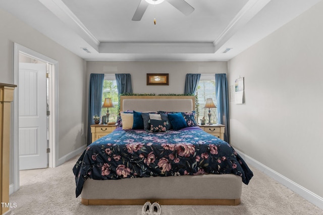 carpeted bedroom with a raised ceiling, multiple windows, and baseboards