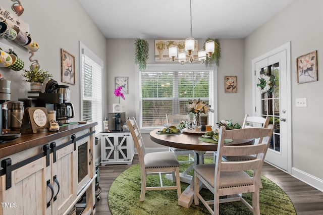 dining space with dark wood-style floors, a chandelier, and baseboards