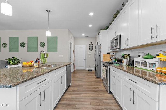 kitchen with decorative backsplash, stainless steel appliances, light wood-style floors, white cabinetry, and a sink