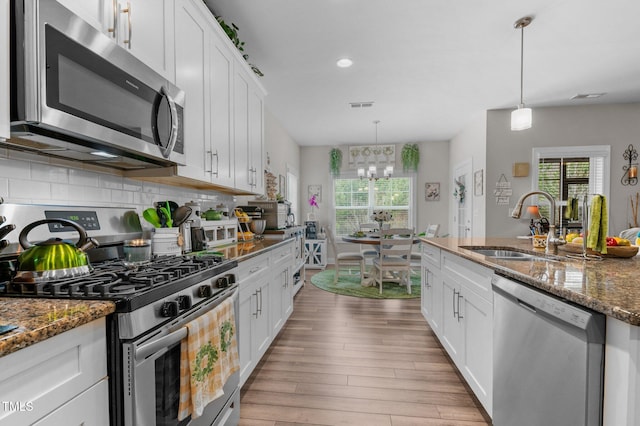 kitchen with a sink, visible vents, appliances with stainless steel finishes, light wood-type flooring, and tasteful backsplash